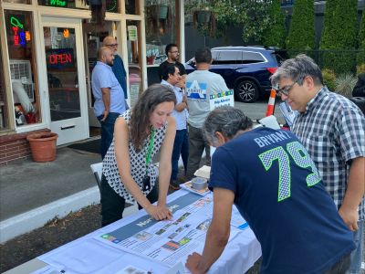 Community members with PCF staff around a table on a sidewalk discussing community selection options